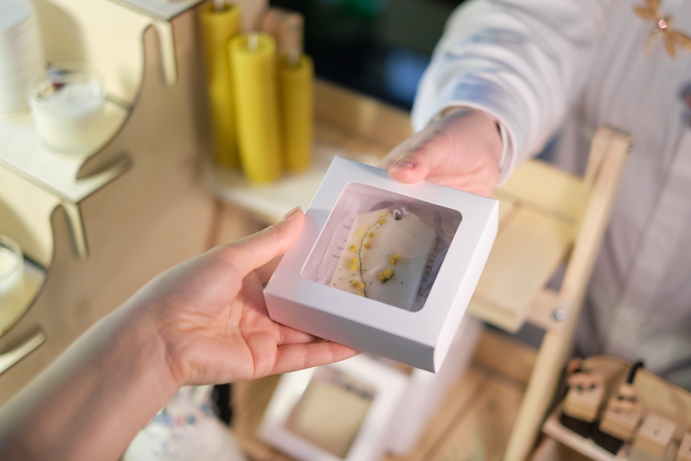Retail worker hands unique packaging to a customer