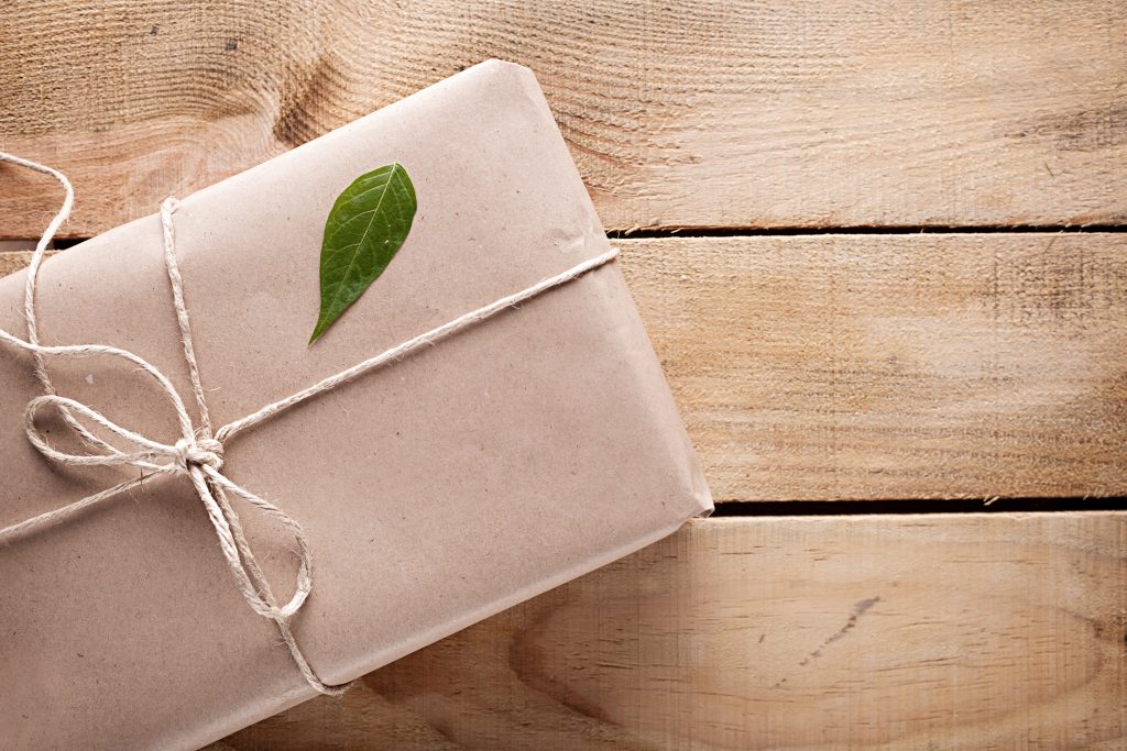 Gift box with a green leaf on a wooden background