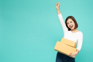 Happy Asian woman holding package and celebrating success