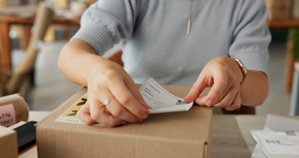 Hands placing a package label for delivery of an e-commerce order